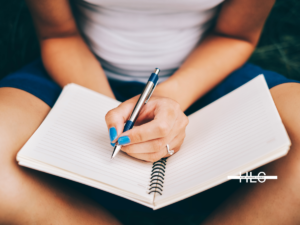 Person with notebook and pen sitting.